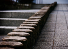 Das Bild zeigt eine Treppe und rechts daneben eine Rampe. Zwischendrin sind zylinderförmige Steine, die Treppe und Rampe trennen.